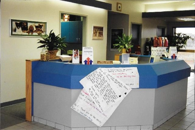 Reception desk with plants and a thank-you note taped on.